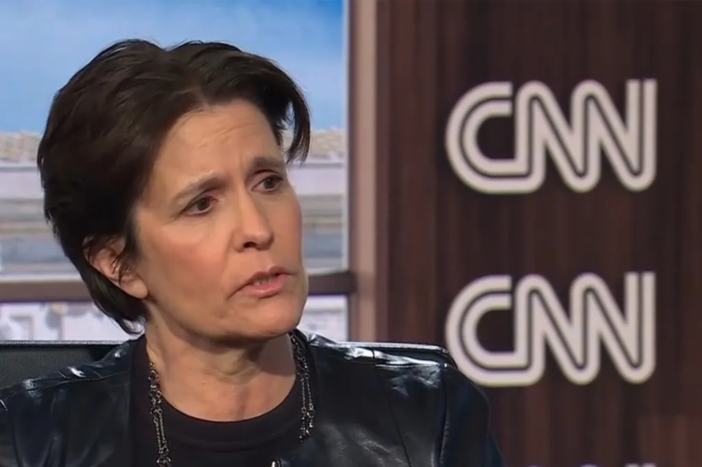 Kara Swisher in a black leather jacket with a CNN logo in the background.