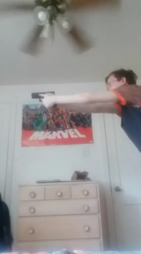 Thomas Matthew Crooks aiming a handgun at a Marvel poster in his room.