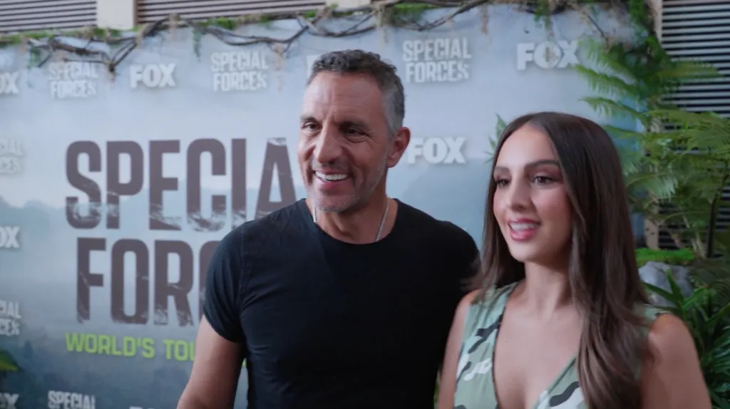 Farrah Aldjufrie and a man with graying hair, smiling in front of a 