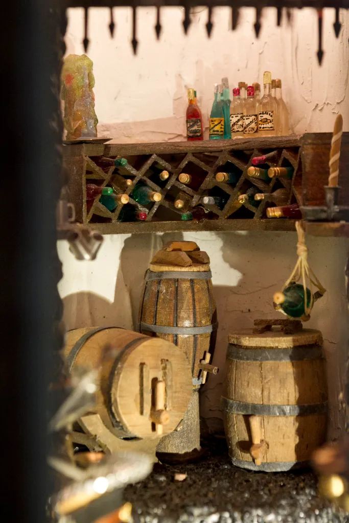 Miniature wine cellar inside the Astolat Dollhouse Castle, with tiny wine bottles, barrels, and a candle.