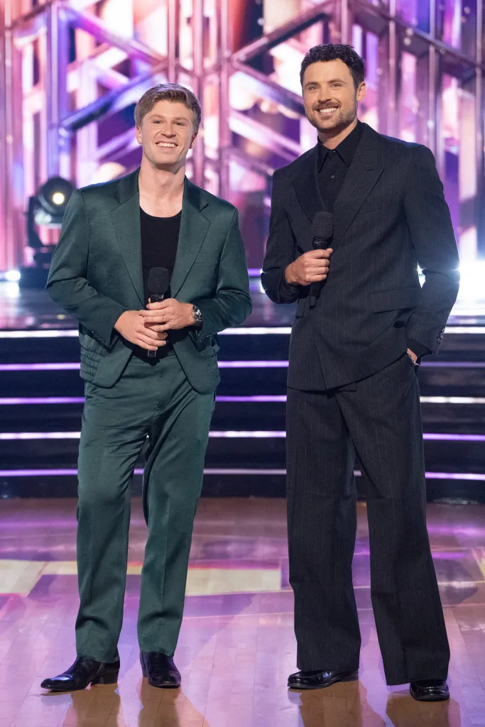 Robert Irwin and Dylan Efron holding microphones, smiling on a stage.