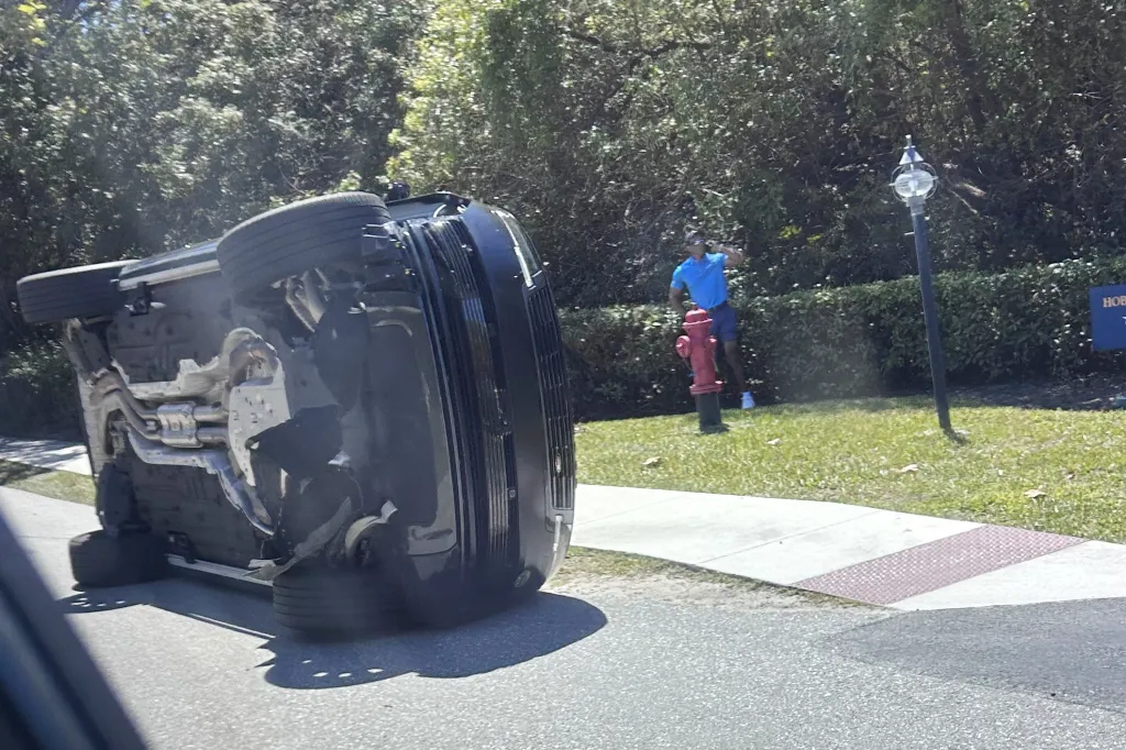 Golfer Tiger Woods stands by his overturned vehicle.