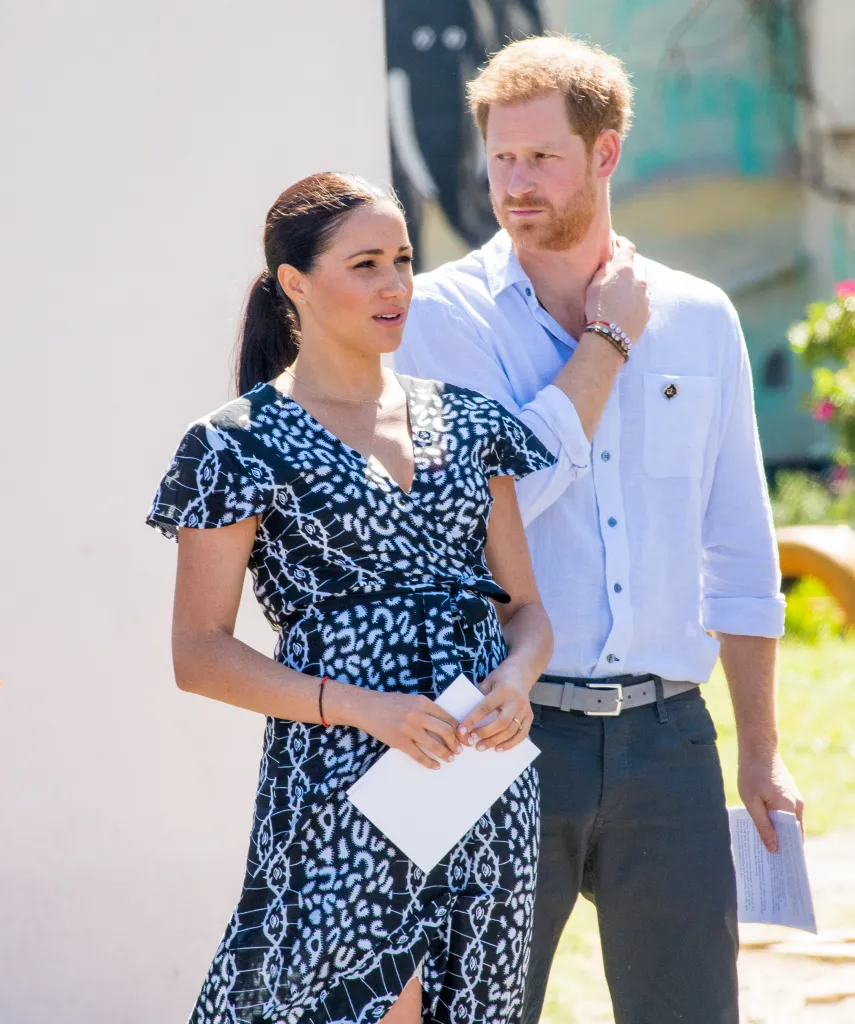 Meghan Markle holding a piece of paper and Prince Harry with his hand to his neck.