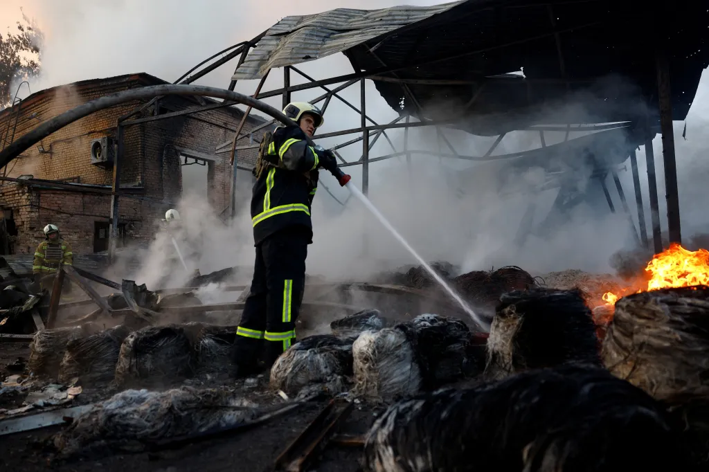 A firefighter sprays water on a burning private enterprise in Kyiv after a Russian missile and drone attack.