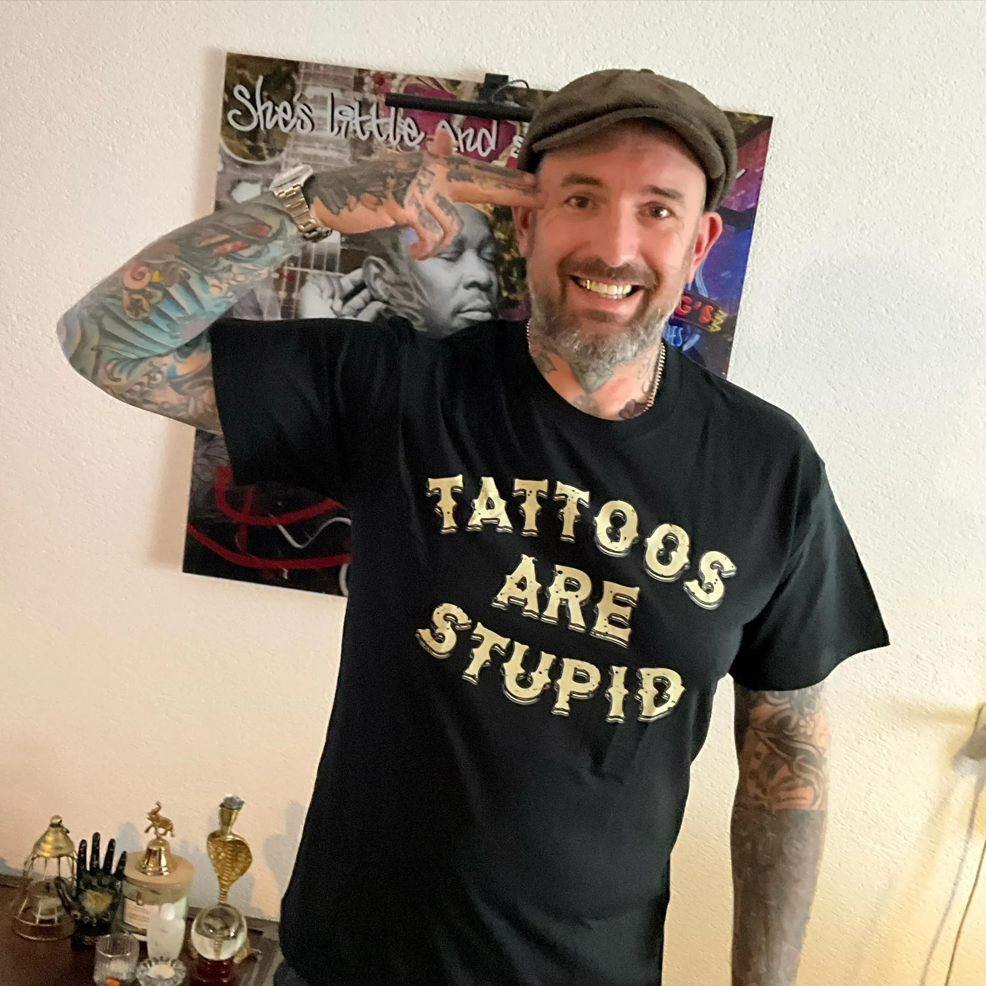Ben Saunders smiling with one hand raised to his temple, wearing a black t-shirt that reads 