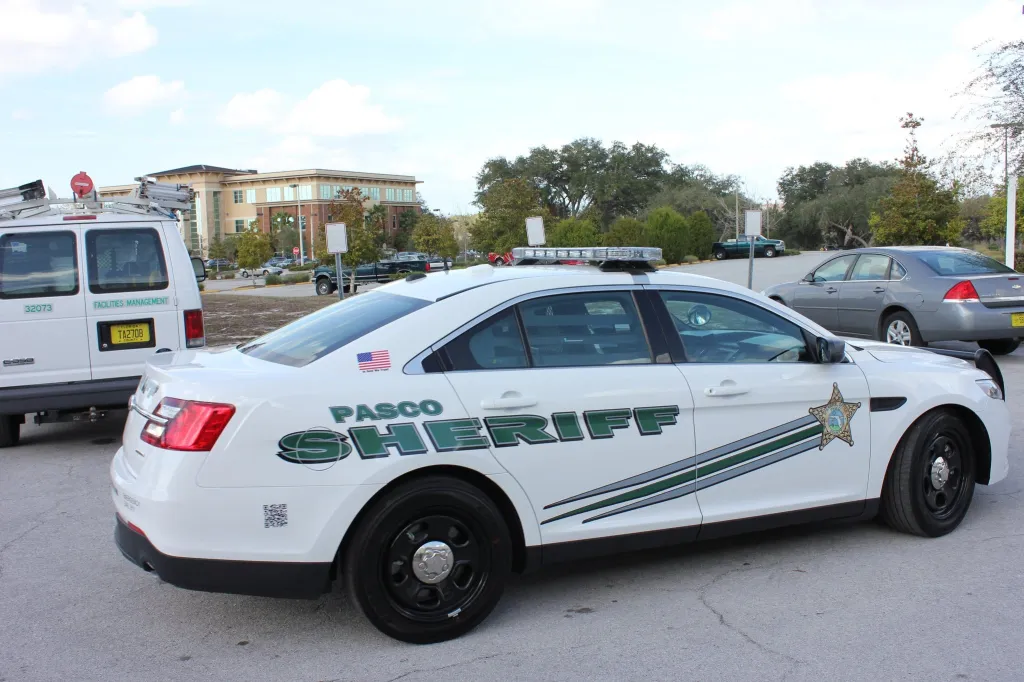 A white Pasco Sheriff patrol car with green lettering and stripes.