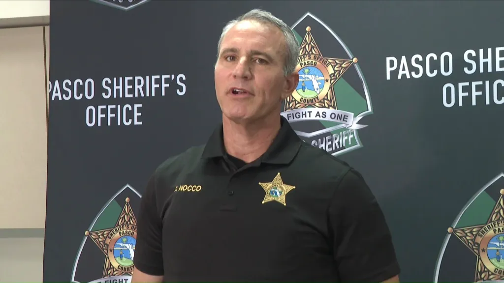 Sheriff Chris Nocco speaking at a press conference in front of a Pasco Sheriff's Office backdrop.