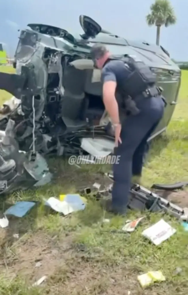 Police officer searching for a survivor in a severely mangled car after a crash.