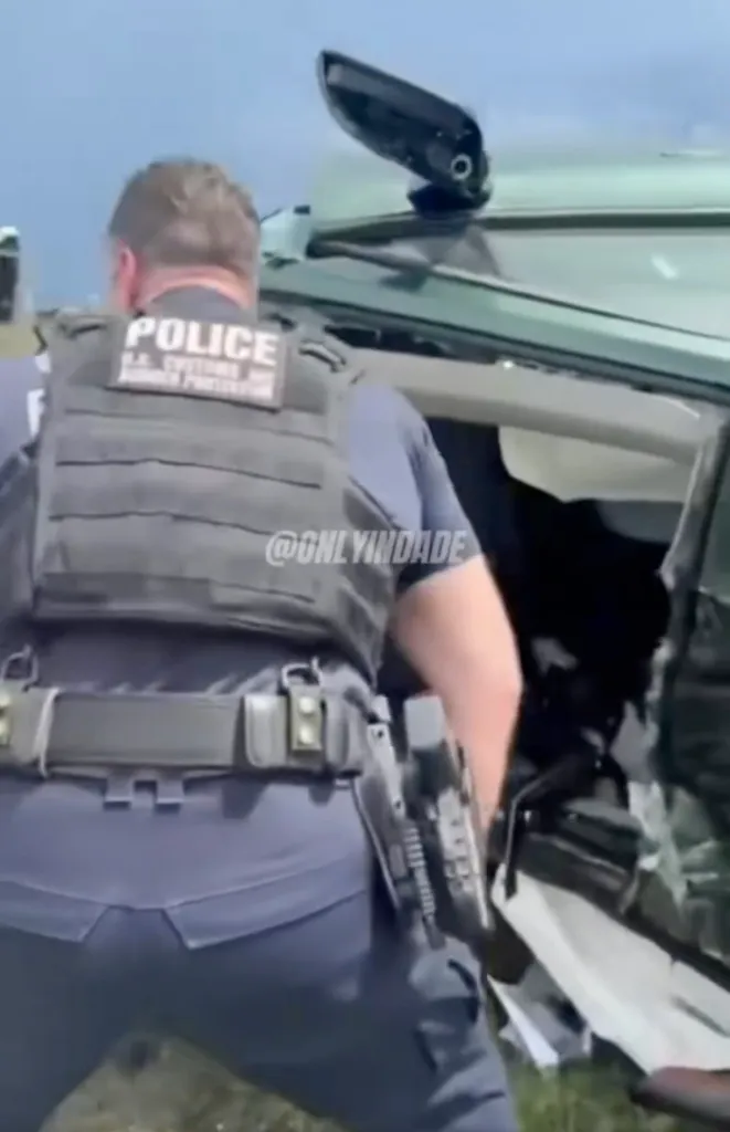 A police officer looks into a mangled car after a crash.