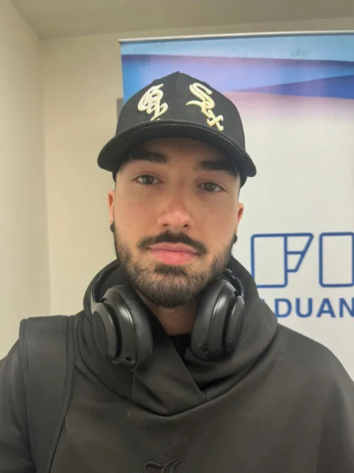 Braiden John Wilson wearing a black baseball cap and headphones around his neck.