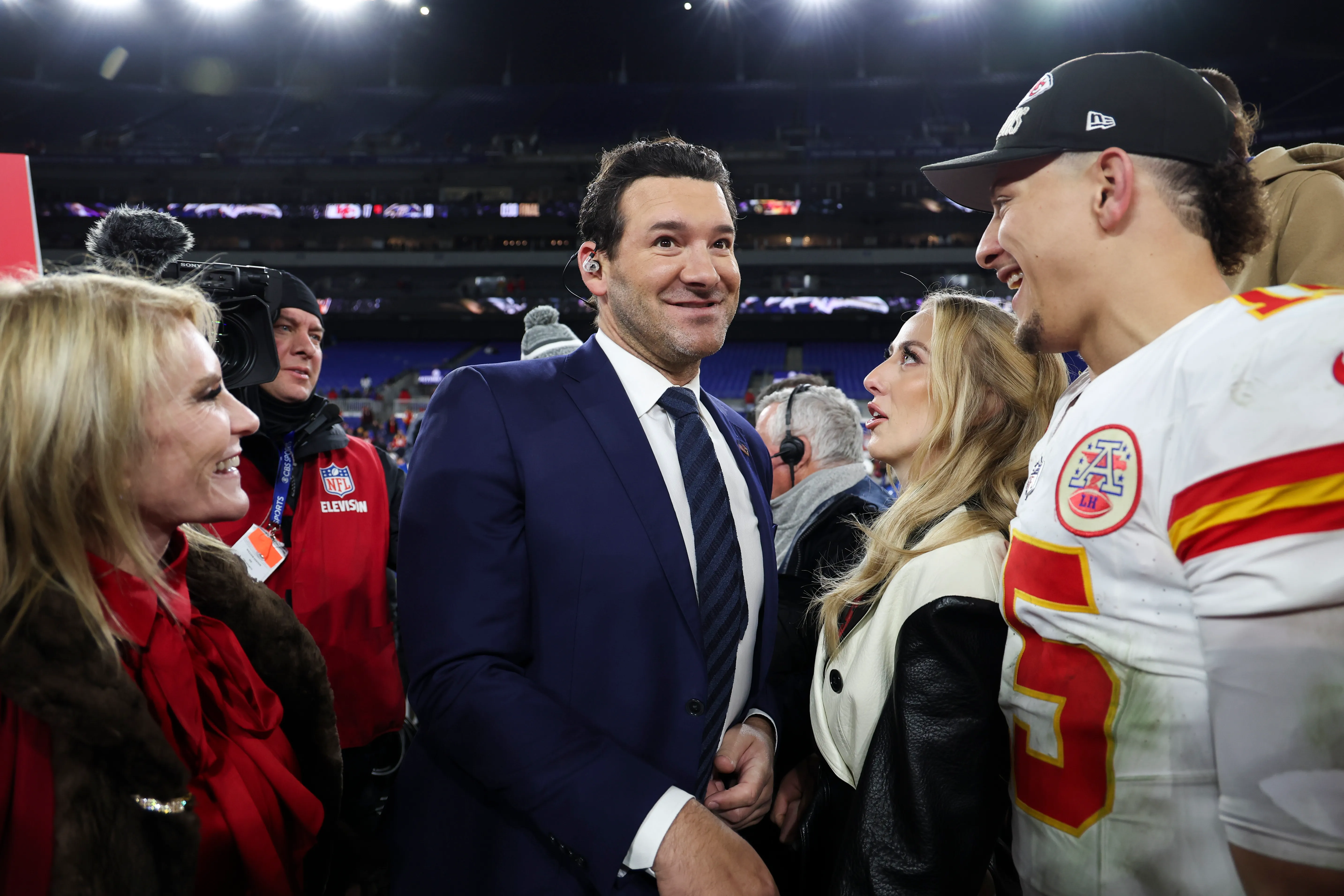 Tony Romo talks with Patrick Mahomes and Brittany Mahomes after the AFC championship game.