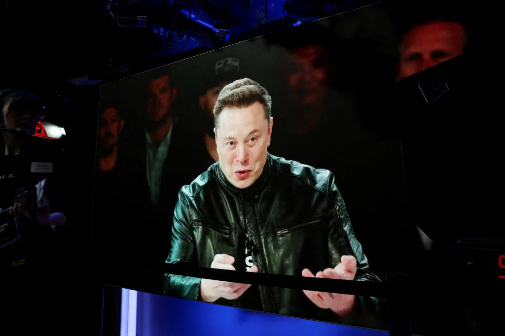 Elon Musk speaking via videolink on a large screen at the Nasdaq MarketSite.