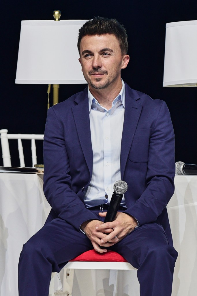 Frankie Muniz seated and holding a microphone at a presentation for 