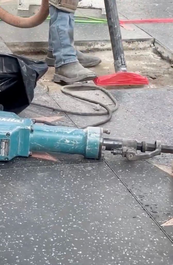 A jackhammer and other construction equipment on a sidewalk.