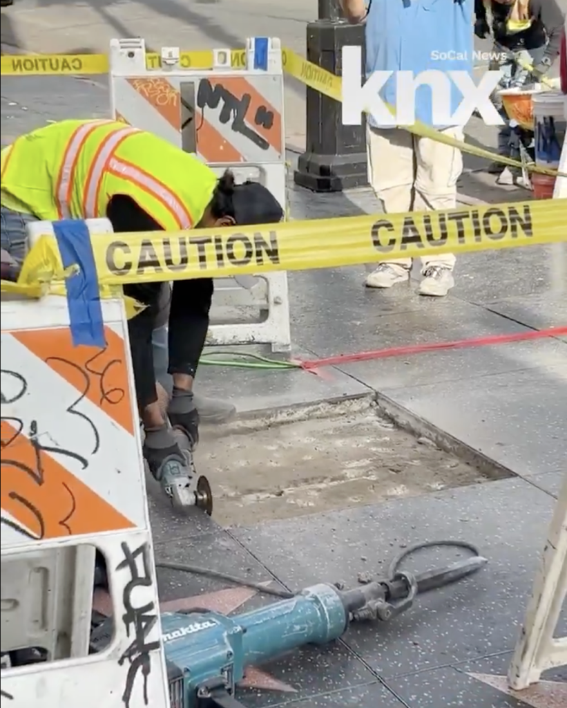 A construction worker repairs a damaged star on the Hollywood Walk of Fame.
