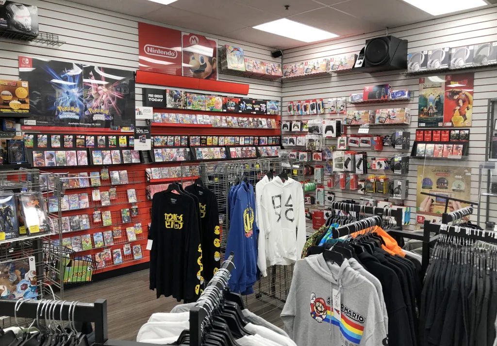 Interior of a GameStop store with shelves stocked with video games, game accessories, and apparel.