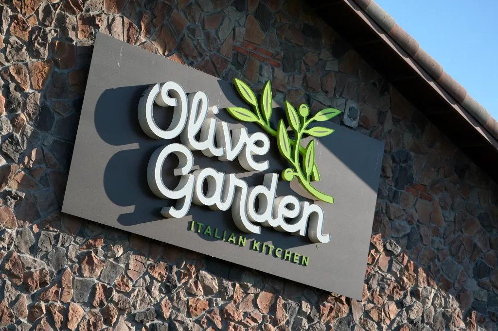 Olive Garden restaurant sign against a stone wall.