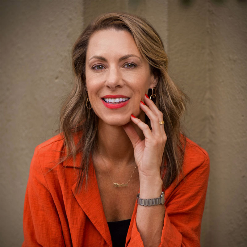 Christina Lacourt smiling and wearing an orange blazer.