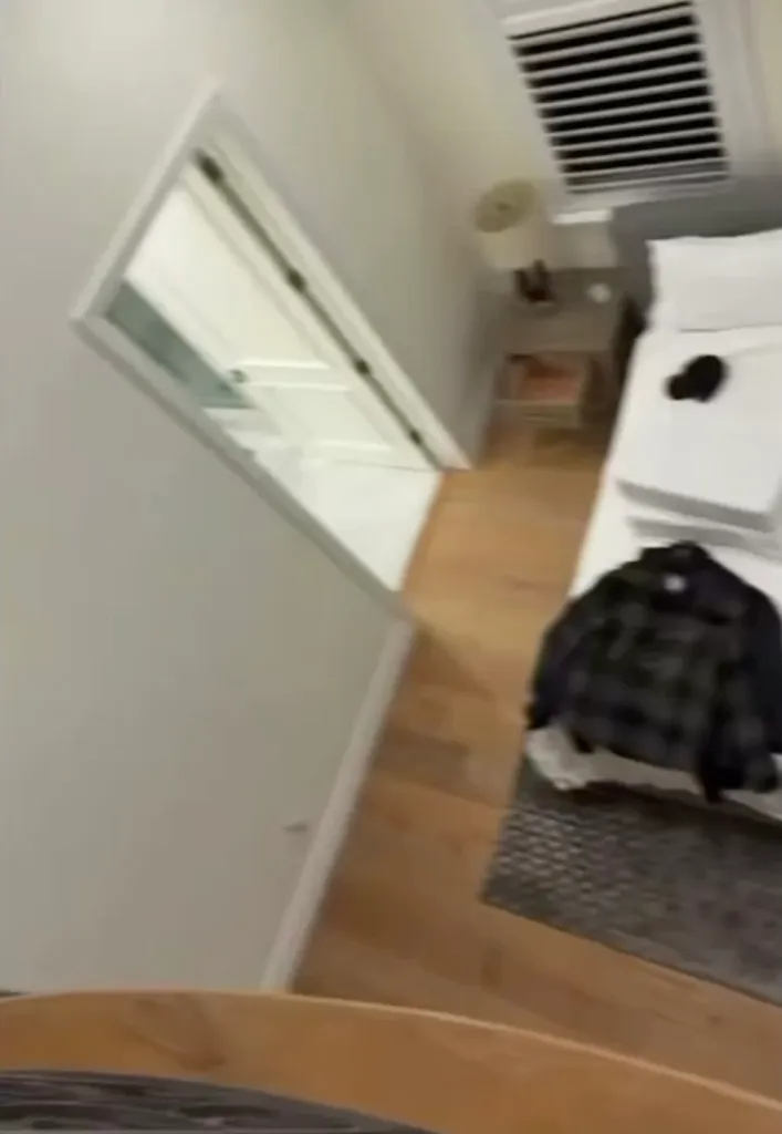 An overhead, blurry view of a bedroom with a bed, a nightstand, and an open door.