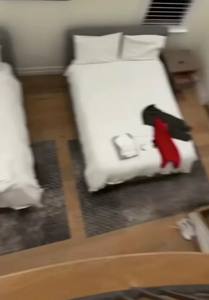 A high-angle view of two twin beds with white sheets and pillows in a rehab facility room.