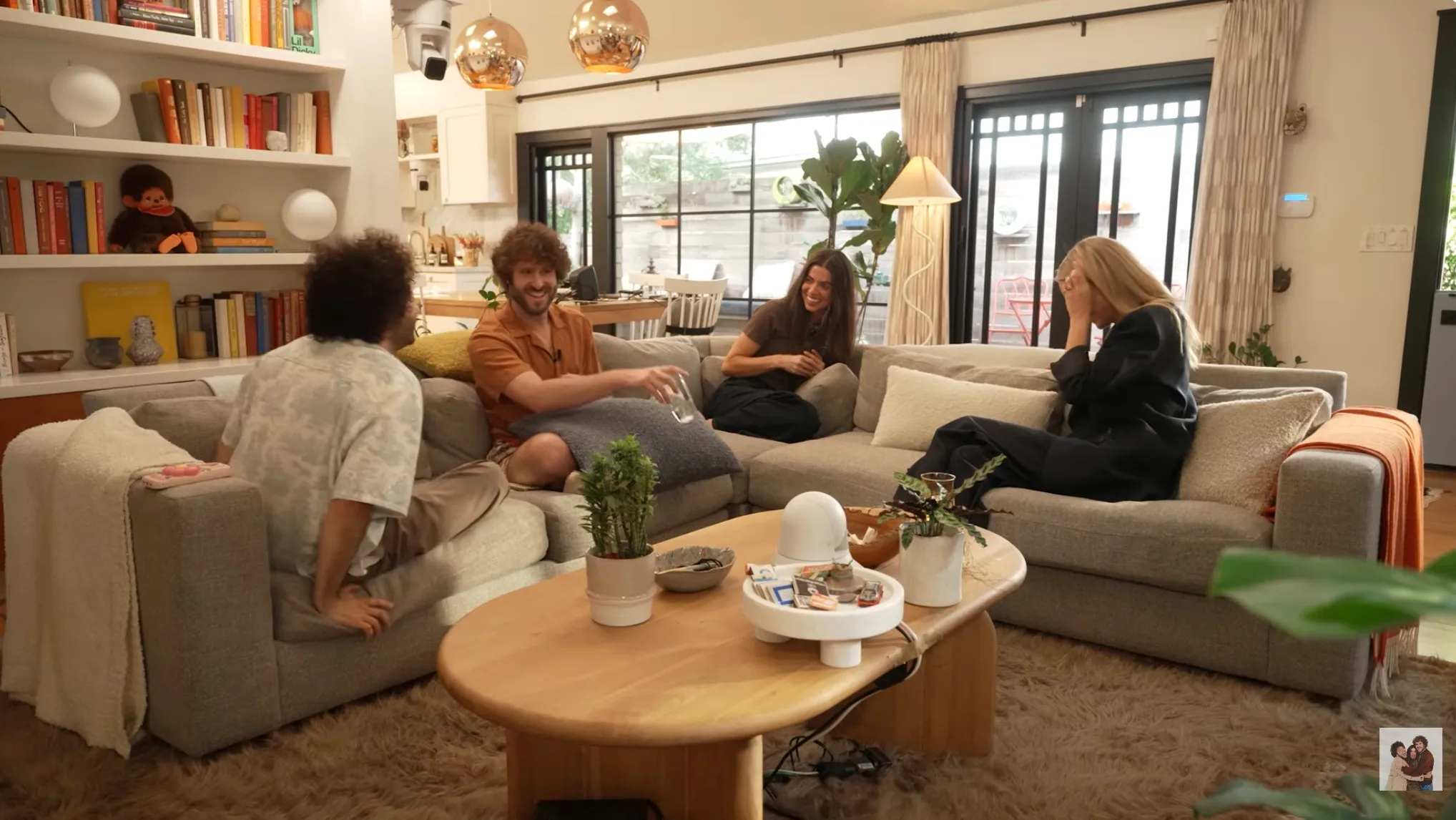 Gwyneth Paltrow covering her face while seated on a couch with three other people.