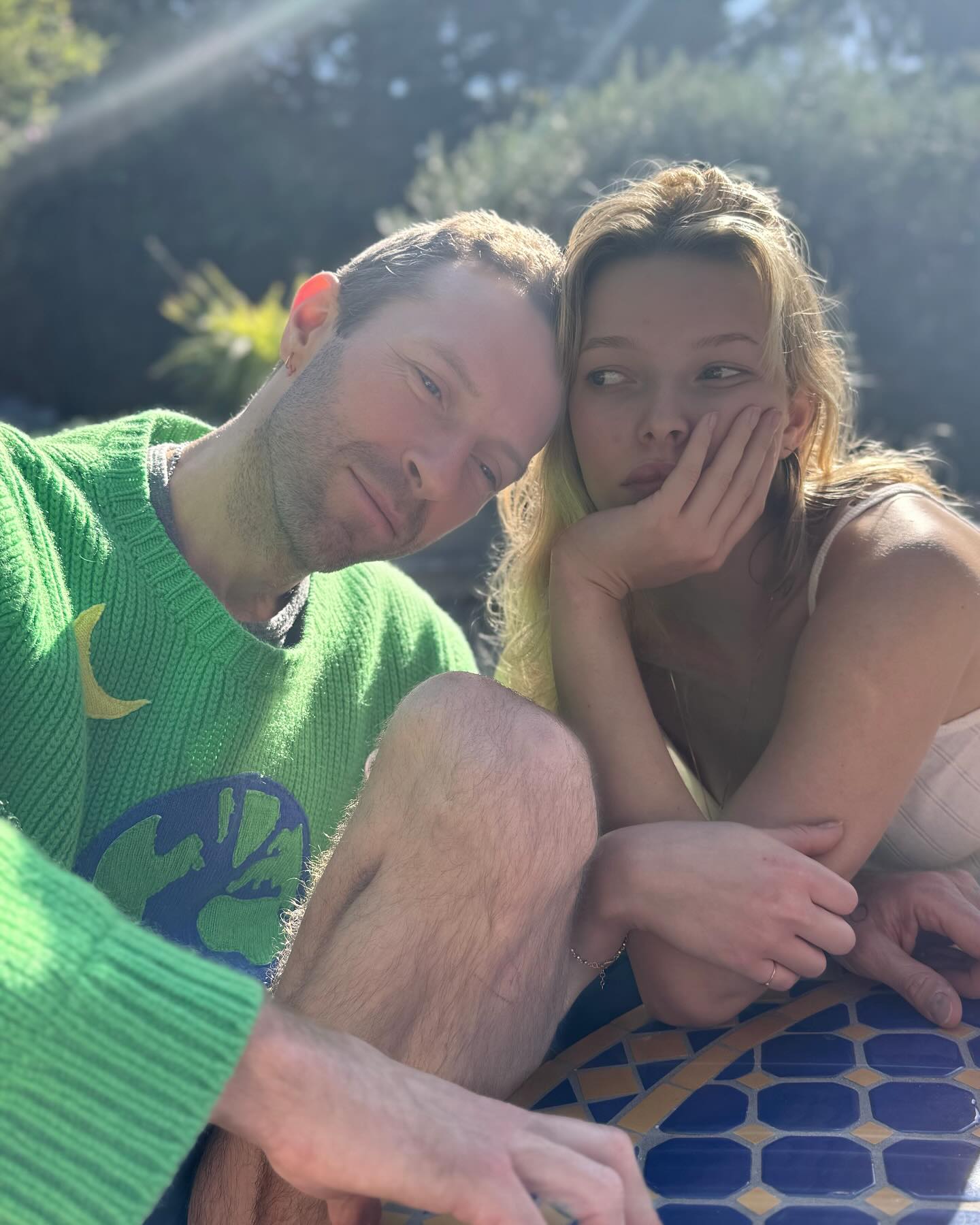 Chris Martin and Apple Martin leaning together outside in the sun.