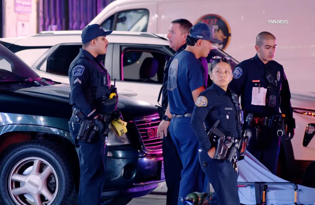 Law enforcement officers and a person wearing a 'Yanez' cap stand near vehicles at a shooting scene in Hawthorne, California.