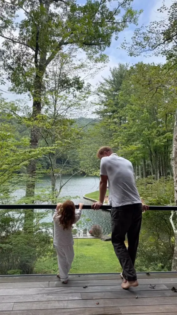 Prince Harry and Princess Lilibet looking out over a lake from a balcony.