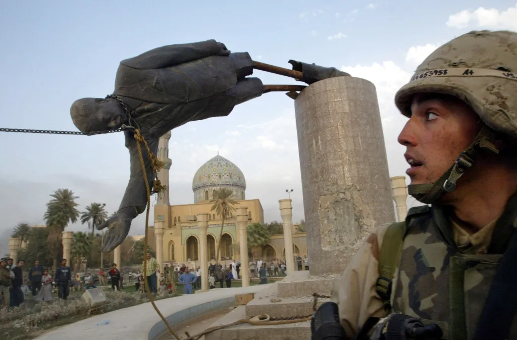 A US soldier watches as a statue of Iraq's President Saddam Hussein falls in central Baghdad, Wednesday, April 9, 2003. U.S. troops pulled down the 20-foot statue of Saddam Hussein, who ruled Iraq for 24 years.