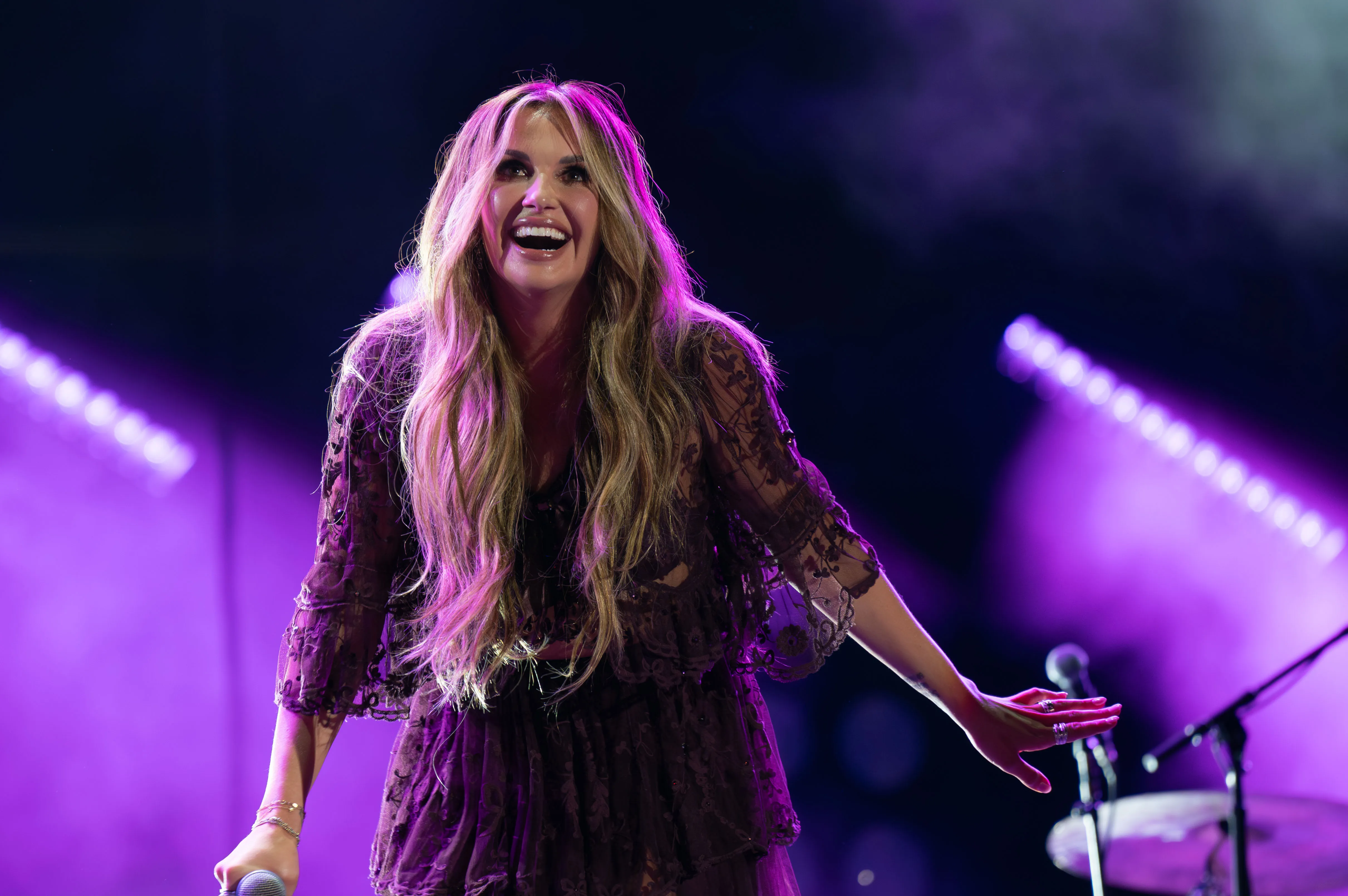 Carly Pearce performing on stage under purple lights.