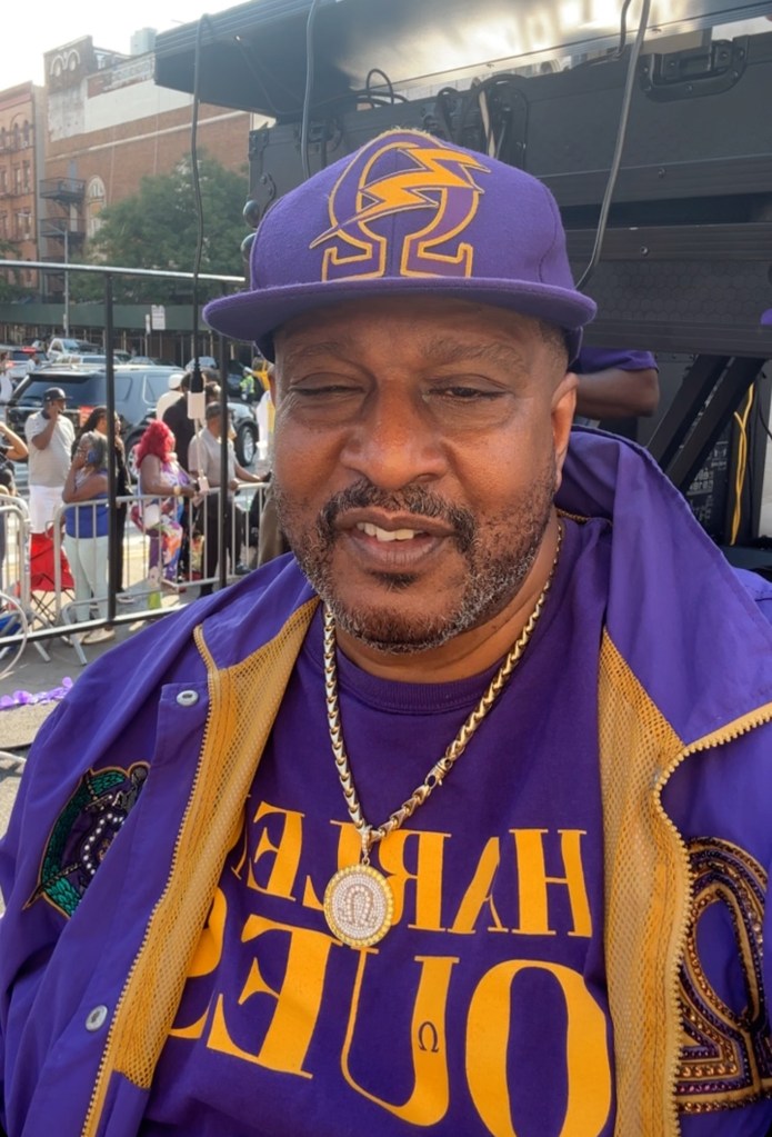 Bodyguard Gene Deal wearing a purple hat, shirt, and jacket.
