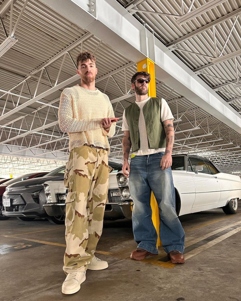 Drew Taggart of The Chainsmokers stands next to another man in a parking garage.
