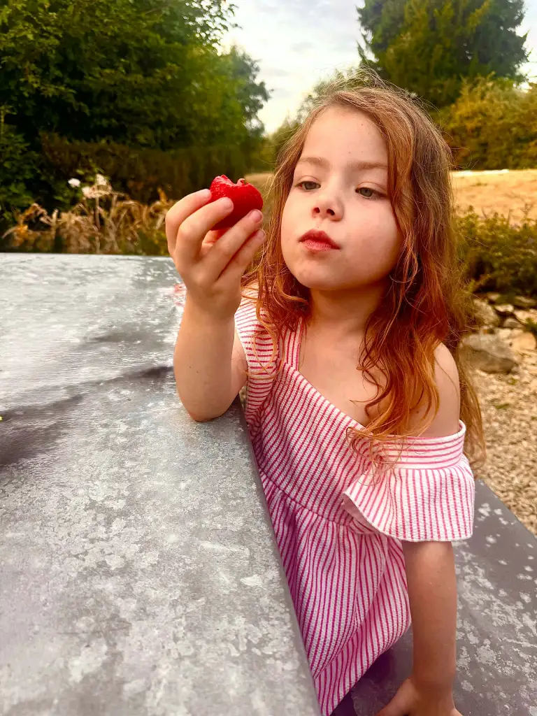 Sienna, diagnosed with central precocious puberty, holding a strawberry.