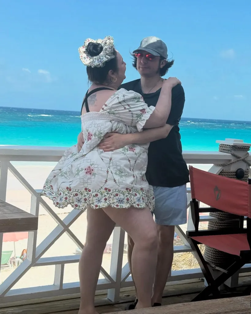 Lena Dunham and Luis Felber embracing on a beachside balcony.