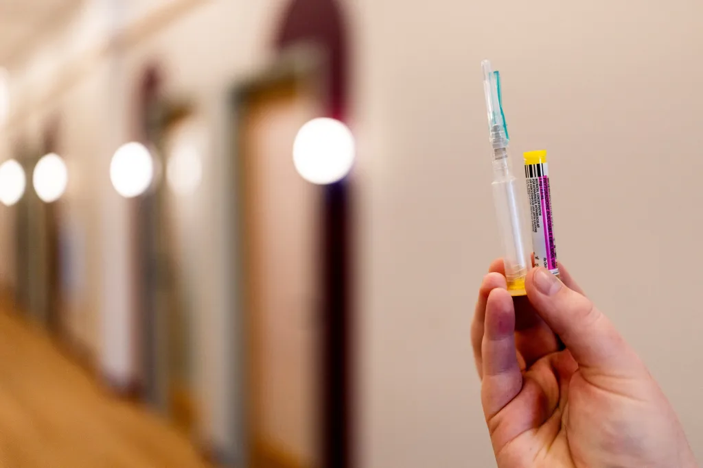 A hand holding a syringe containing Phytonadione, a synthetic version of vitamin K.