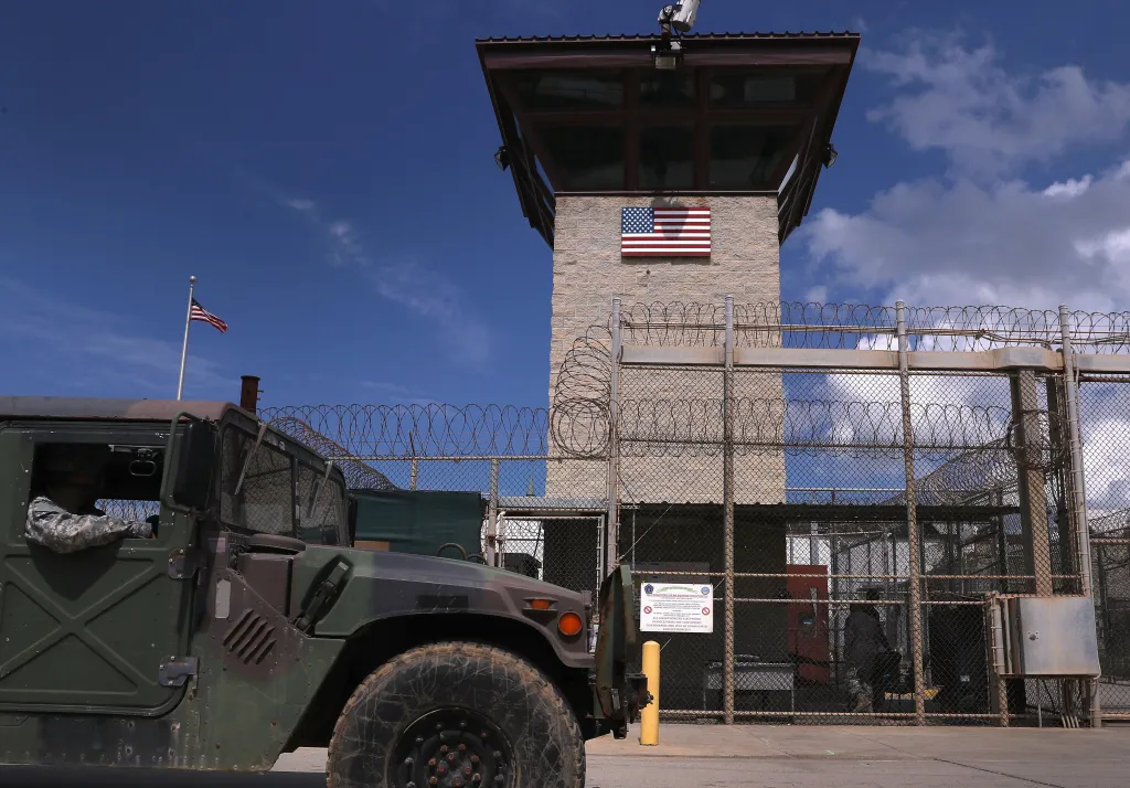 A Humvee passes a guard tower with a US flag at the entrance of the U.S. prison at Guantanamo Bay.