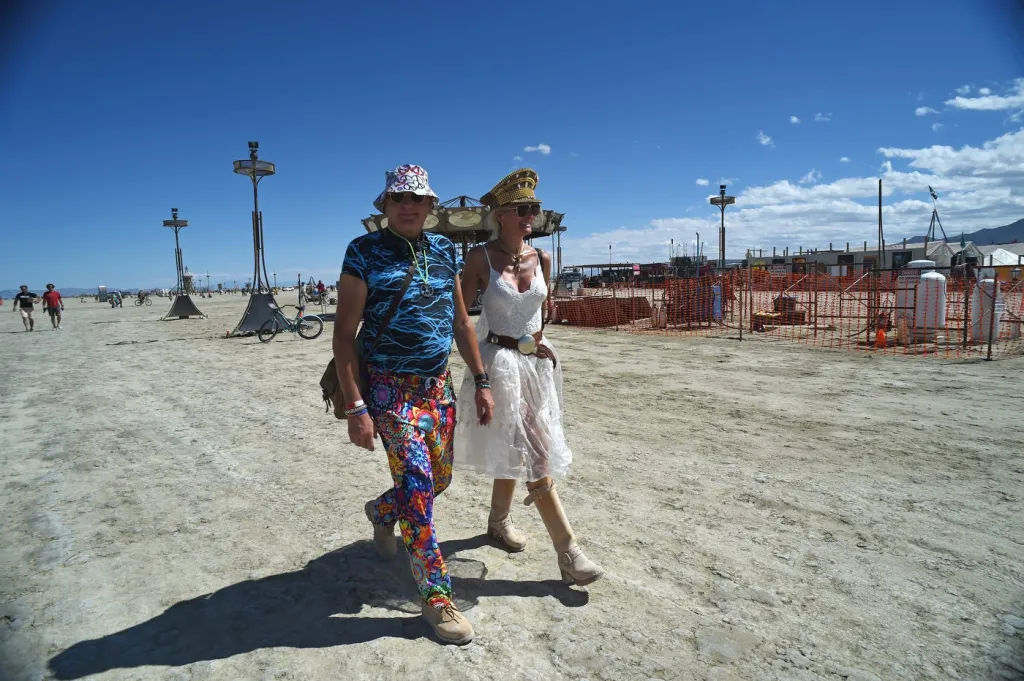 A man and woman walk across the desert at Burning Man.