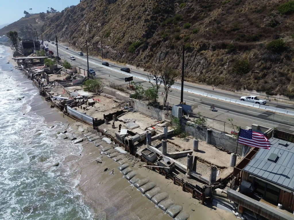 Destruction along the Malibu coast following the 2025 LA wildfires, with a highway running parallel to the damaged beachfront properties.