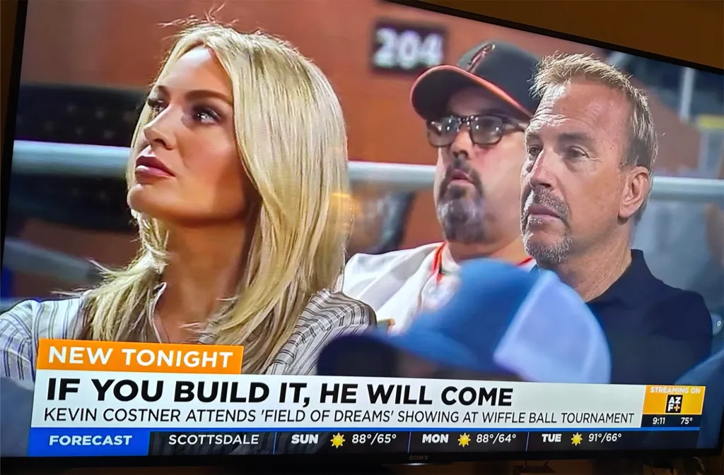 Kevin Costner and an influencer watching a Wiffle ball tournament.