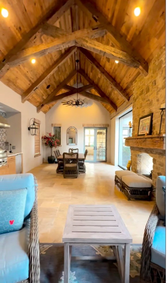 The dramatic great room features a soaring wood ceiling, exposed beams and a stone fireplace.