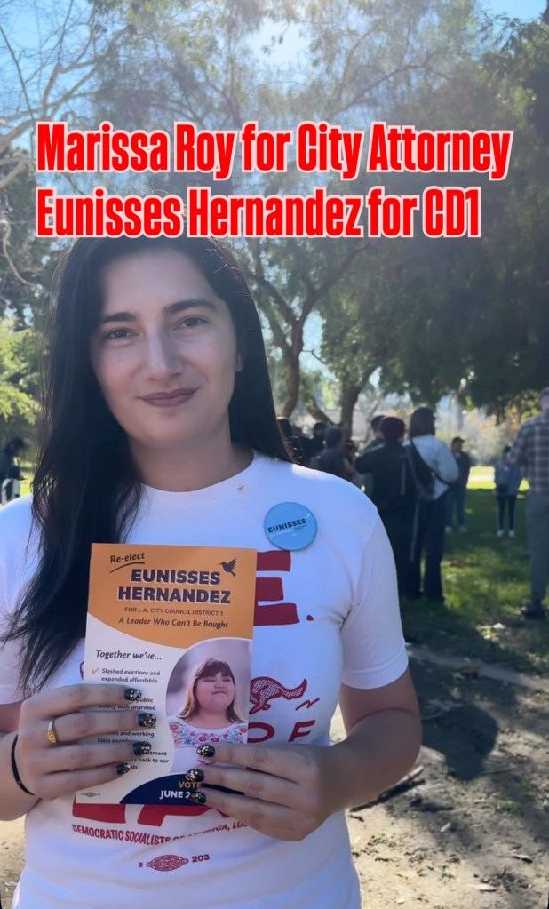 Marissa Roy, a candidate for LA City Attorney, holds a campaign flyer for Eunisses Hernandez.