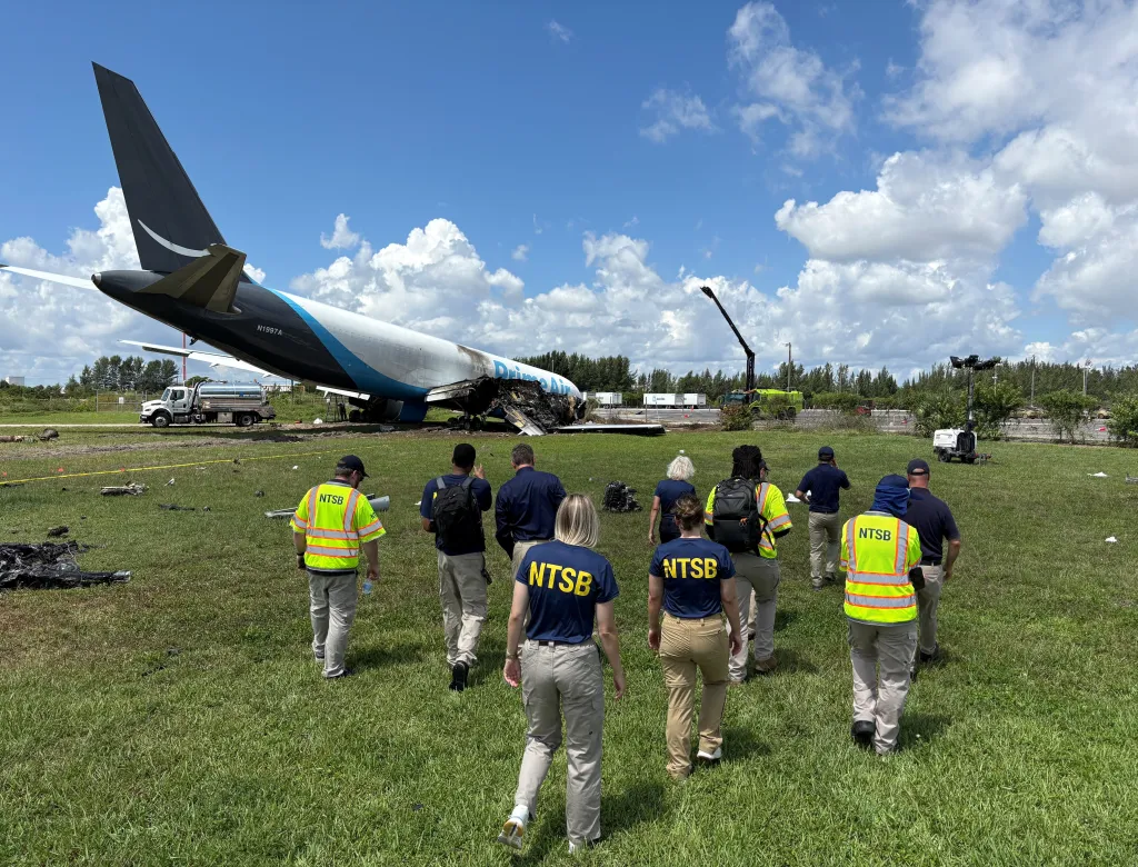 National Transportation Safety Board investigators inspect the site where an Amazon Prime Air cargo plane overran a runway on Monday at Miami International Airport in Miami, Florida.