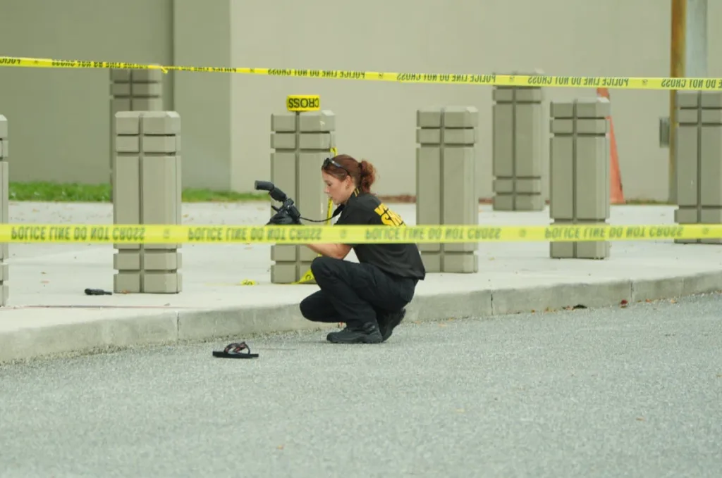 An investigator takes photos at the scene of an active shooter incident, marked by yellow police tape.