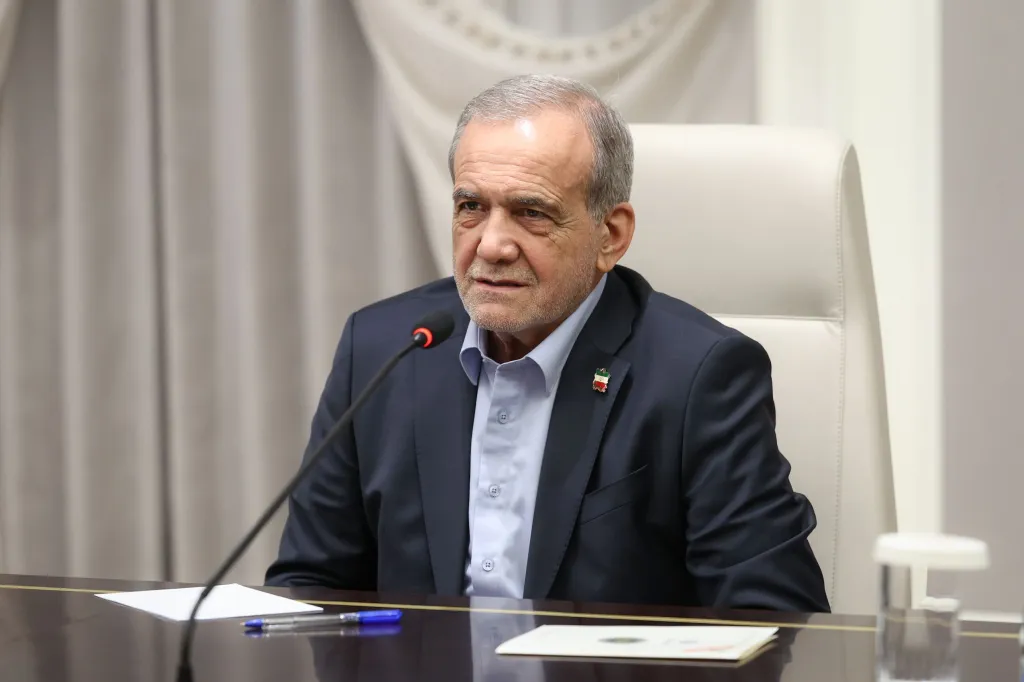 Iranian President Masoud Pezeshkian sitting at a conference table with a microphone in front of him.