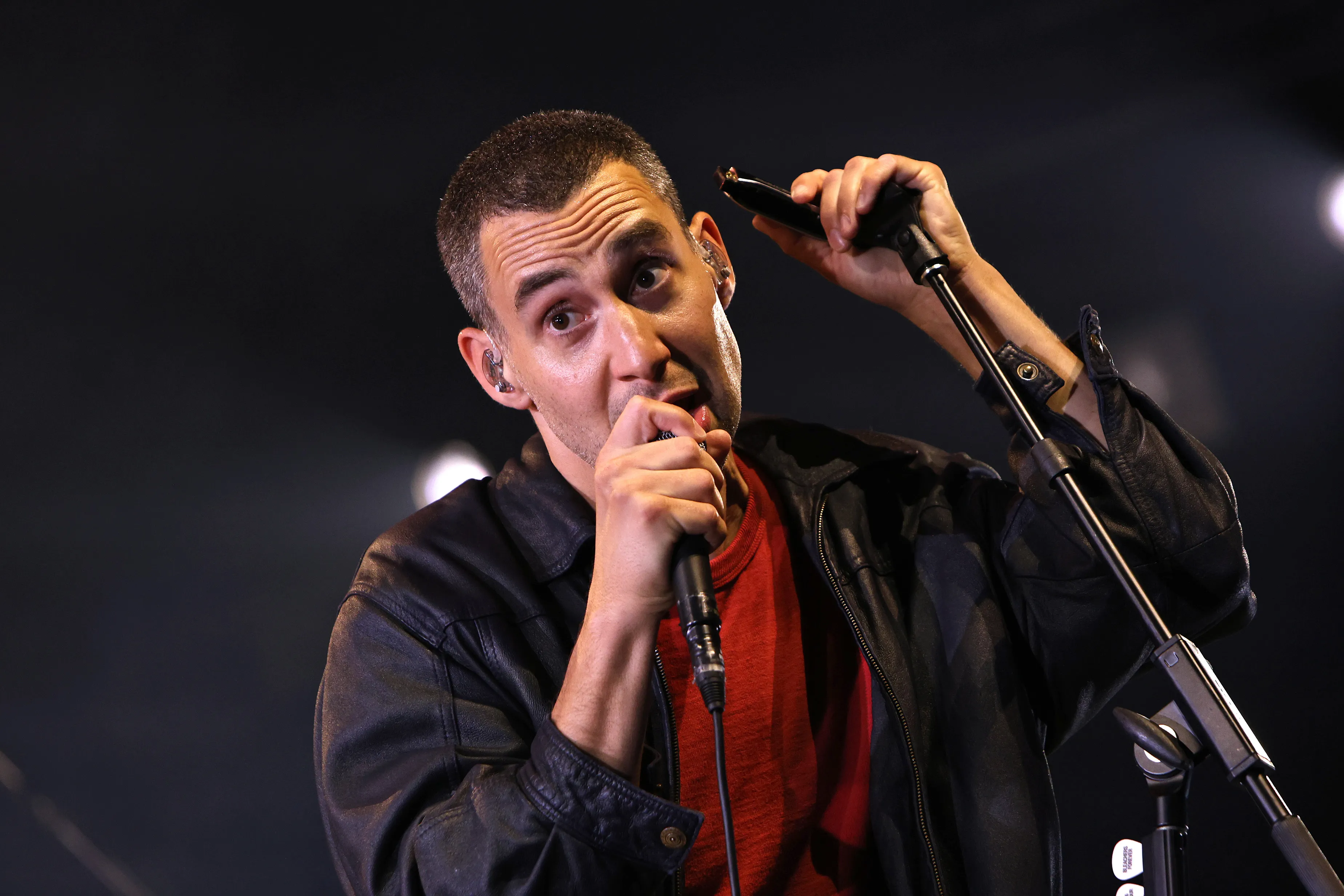 Jack Antonoff performing at RBC Amphitheatre with a microphone and harmonica.