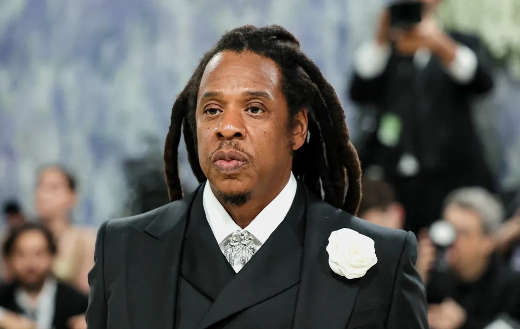 Jay-Z in a black suit with a white rose on the lapel, attending the Met Gala.