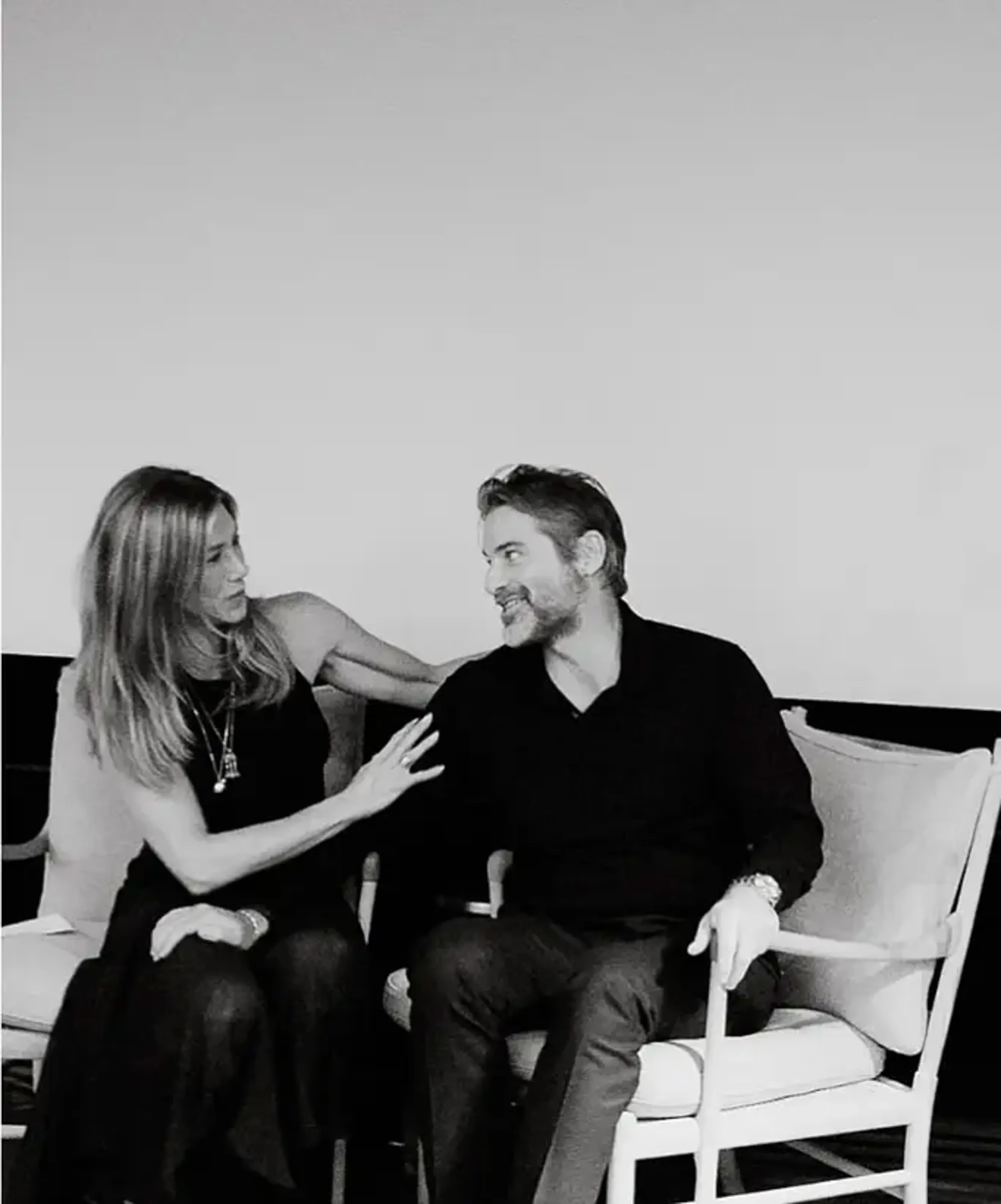 Jennifer Aniston and Jim Curtis sitting on chairs.