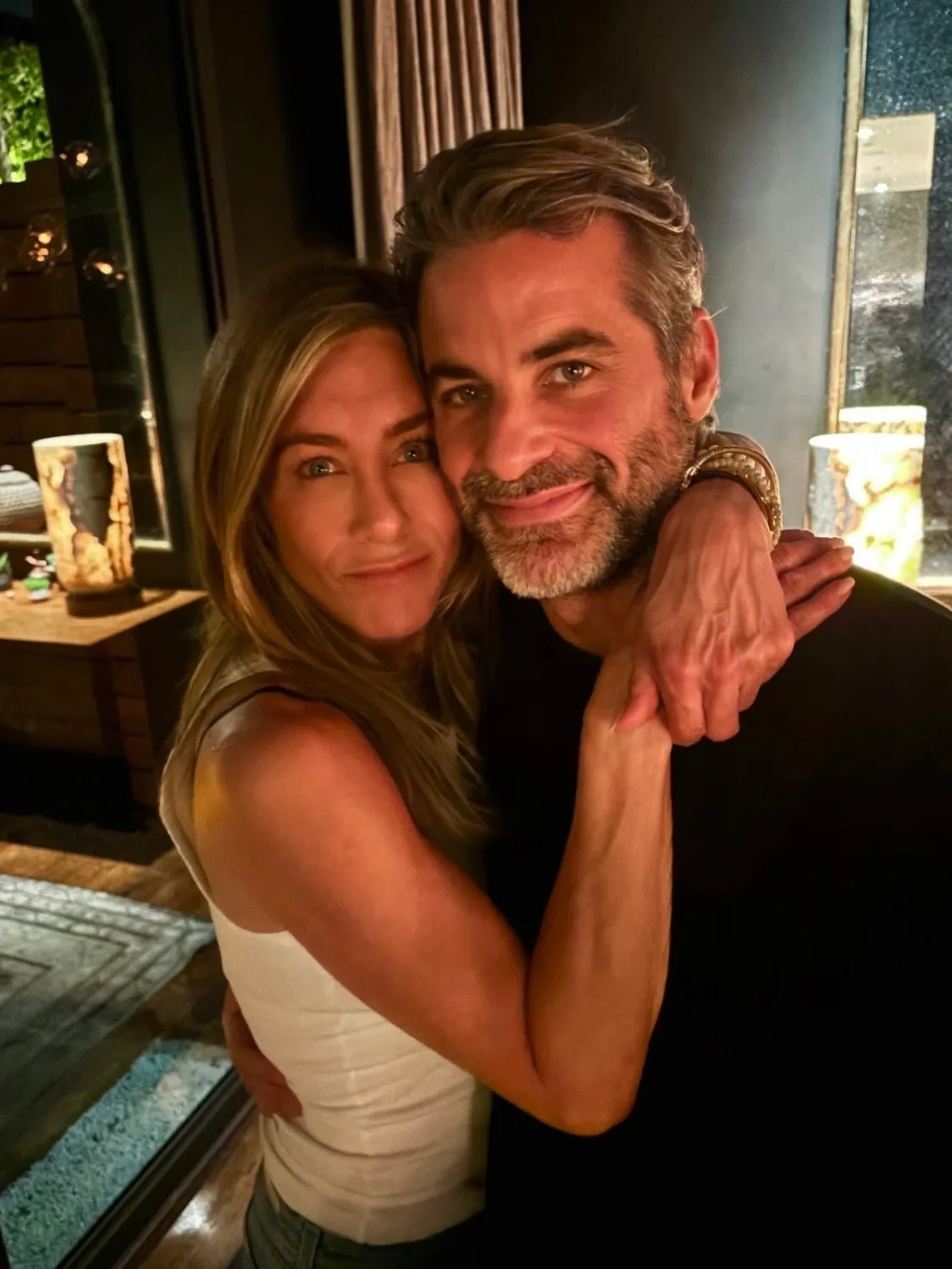 Jennifer Aniston and Jim Curtis embracing and smiling at the camera.