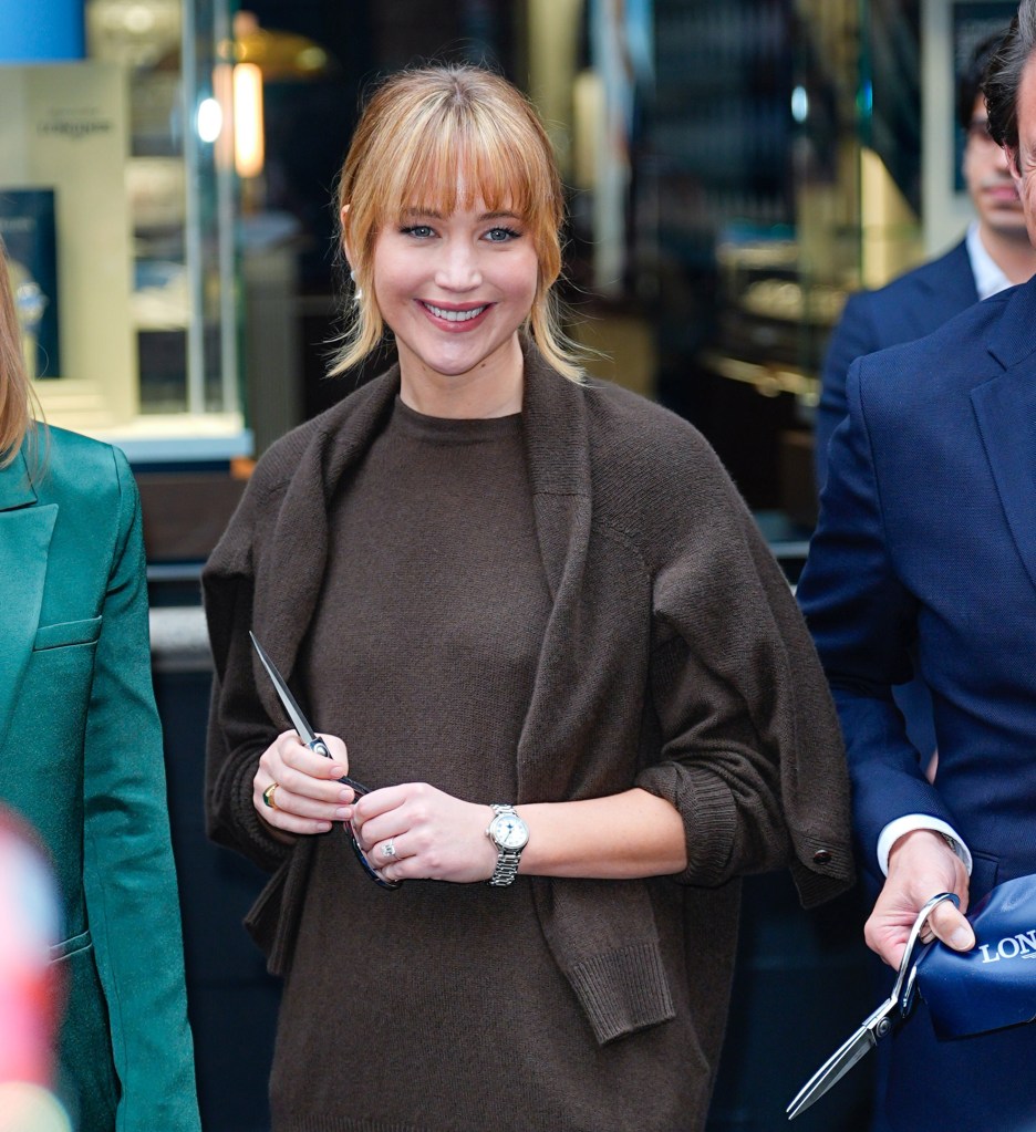 Jennifer Lawrence holding scissors at a ribbon-cutting ceremony.
