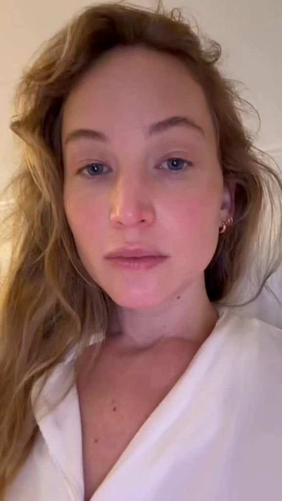 Jennifer Lawrence looking at the camera wearing a white collared shirt.